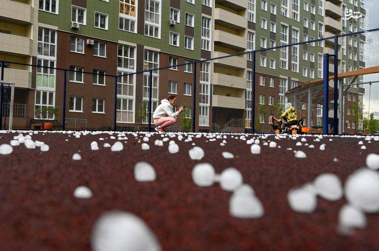 پس از بارش تگرگ در شهر سیبری اومسک روسیه زنی از کودکش عکس می‌گیرد.